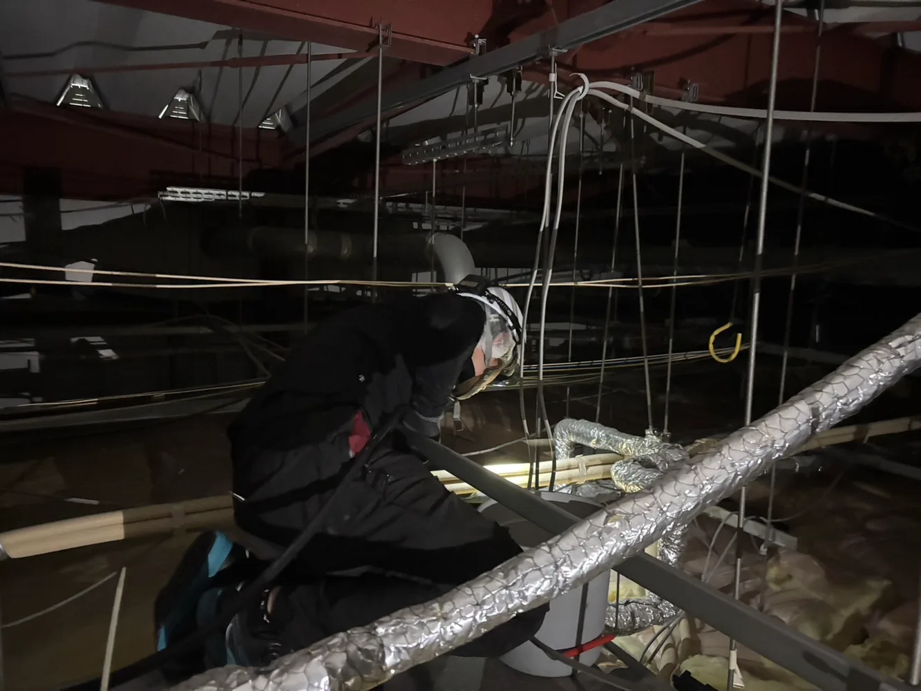天井裏で空調機ドレン配管を洗浄する作業